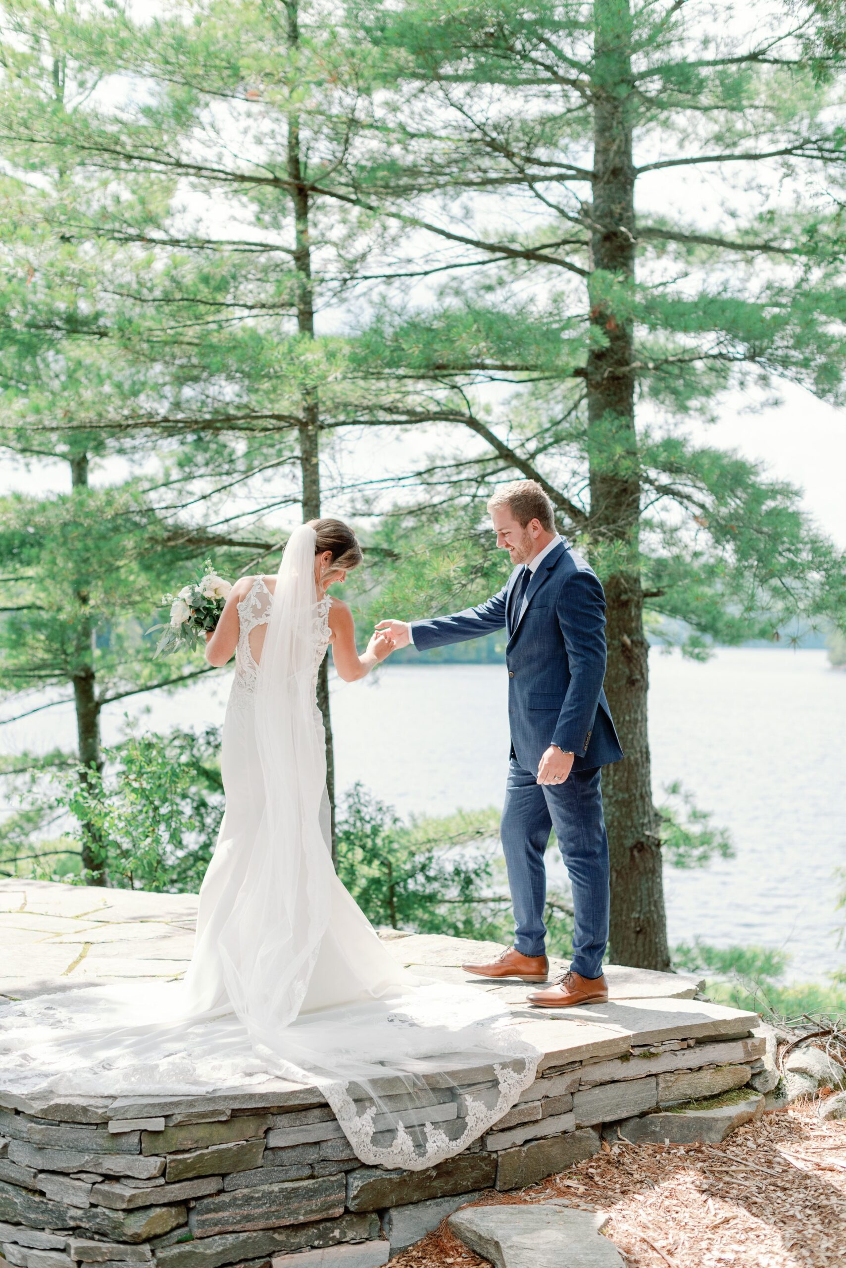 Wedding couple standing next to pine trees on Muskoka lake.
