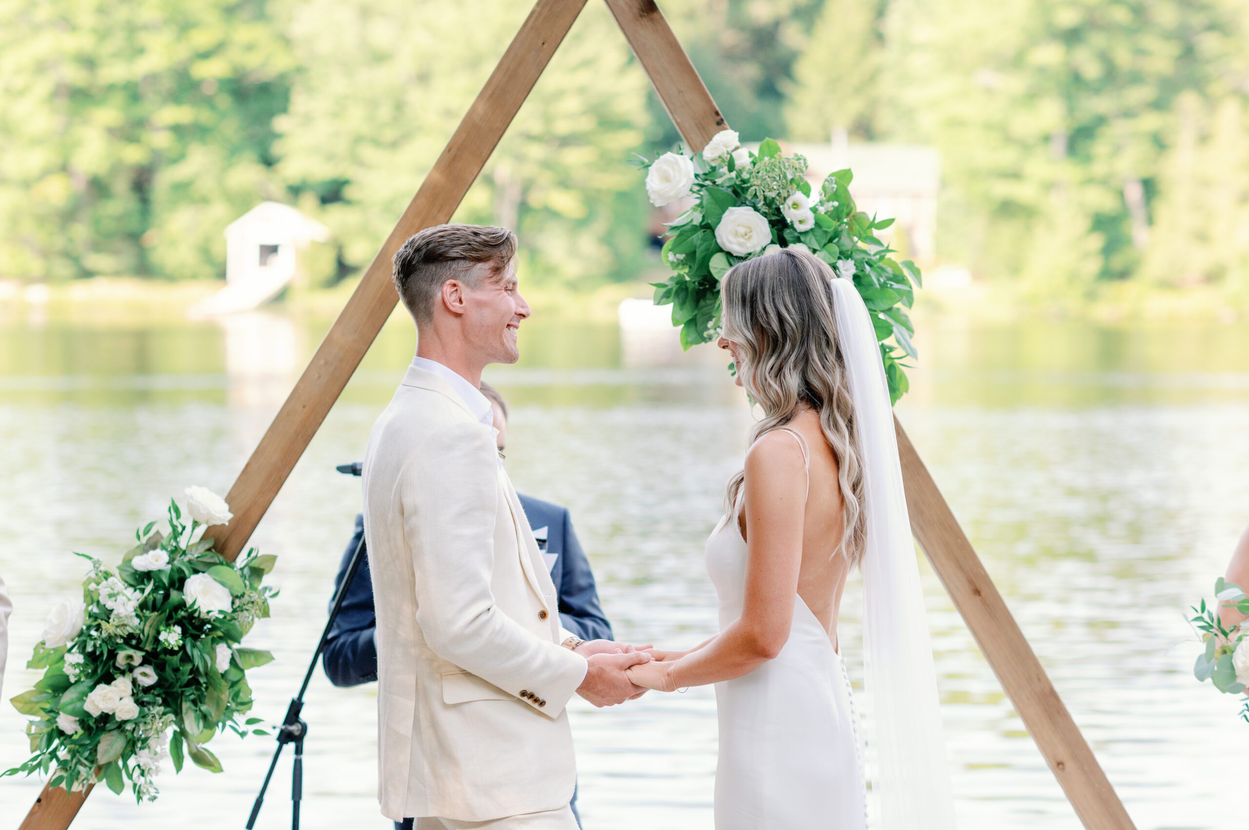 Couple getting married under wooden triangle at Muskoka Lake wedding.