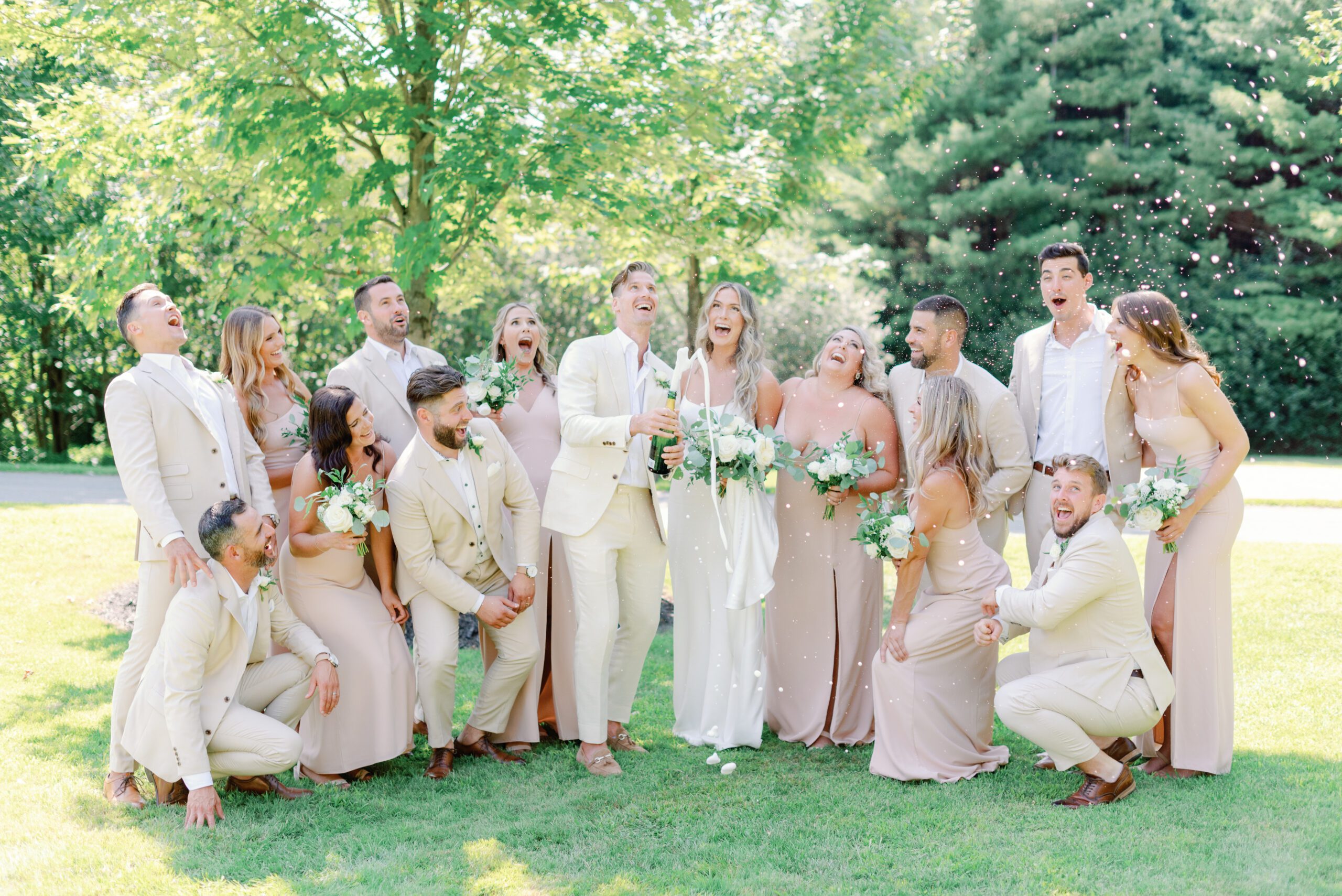 Wedding couple and wedding party laughing while popping champagne.