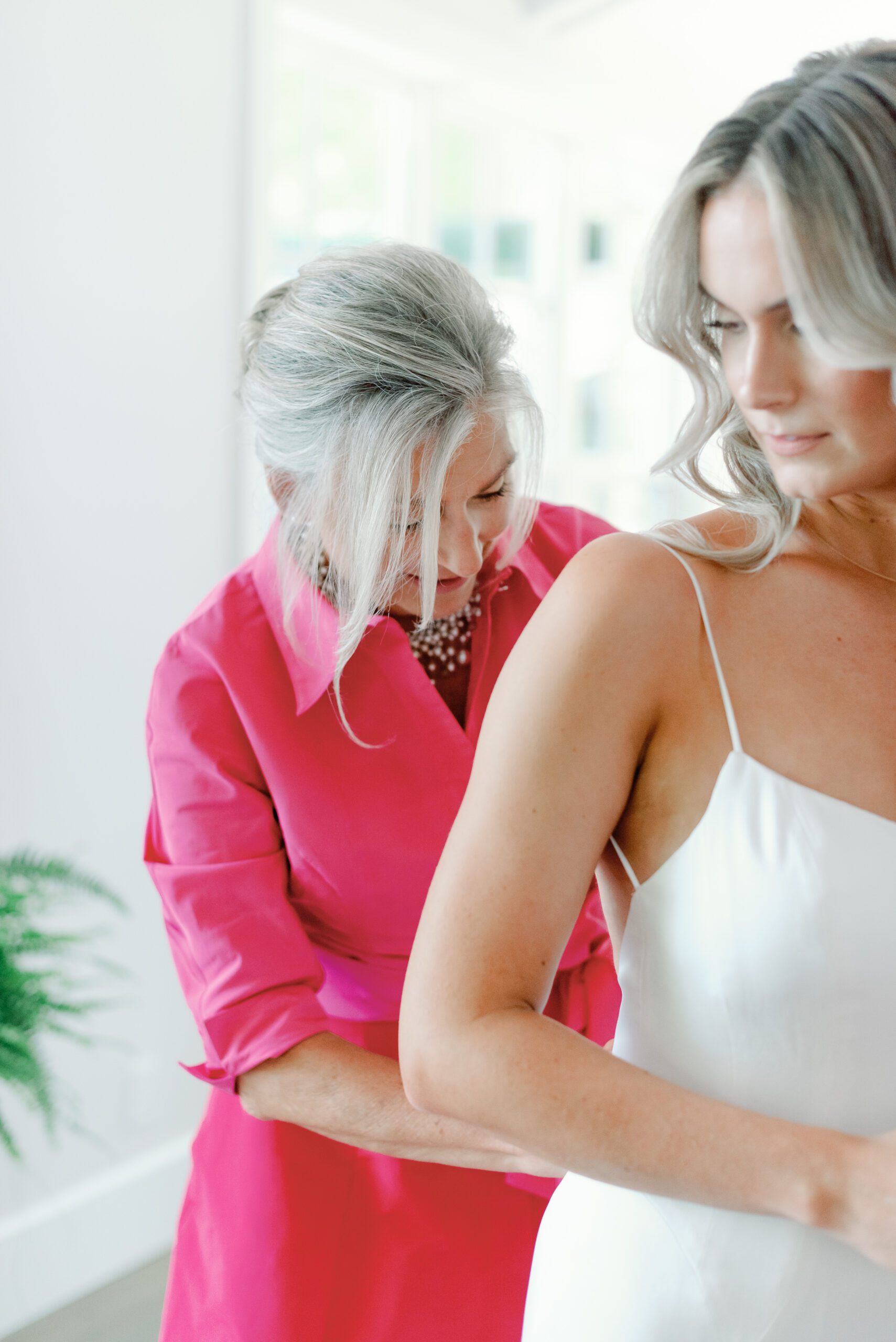 Mother helping bride into wedding dress.